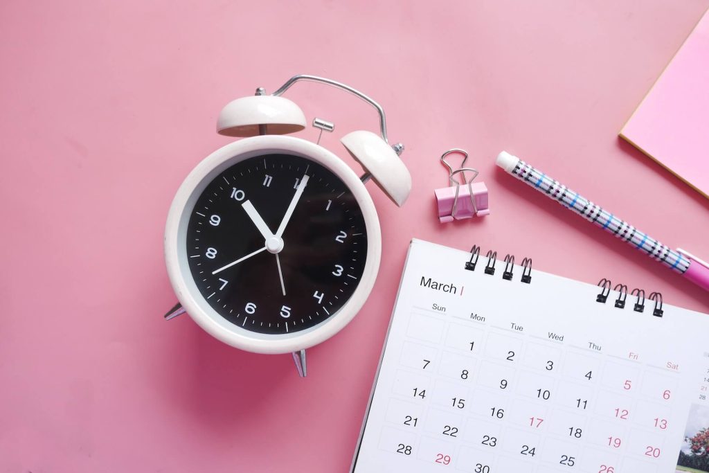 clock and calendar on pink table